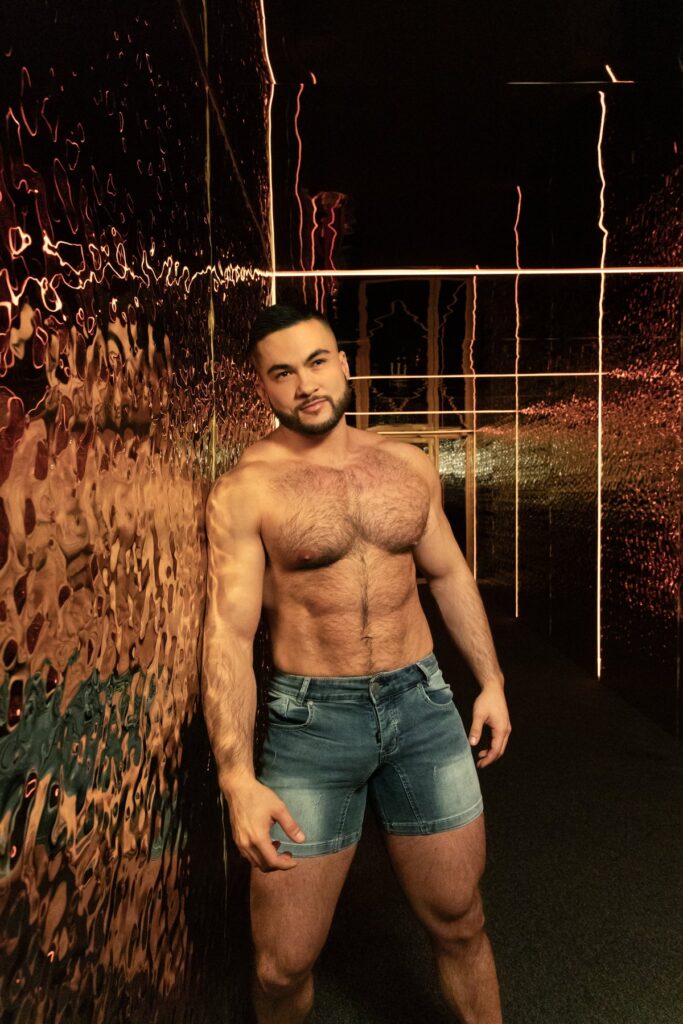 Magabiztos férfi denim shortban egy éjszakai, fényfüzéres helyszínen